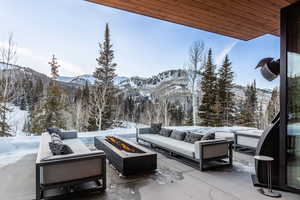 Snow covered patio with an outdoor living space with a fire pit, a patio, and a mountain view