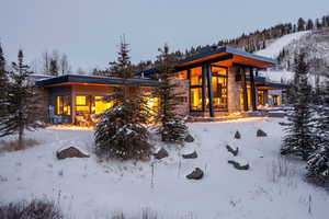 Snow covered house featuring stone siding