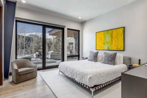 Bedroom with a mountain view, access to outside, light wood-style flooring, and recessed lighting