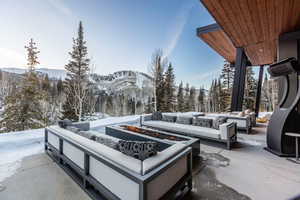Snow covered patio with a patio area, an outdoor living space with a fire pit, and a mountain view