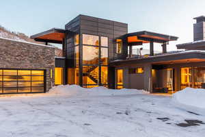 Contemporary house featuring a balcony, stone siding, and a garage