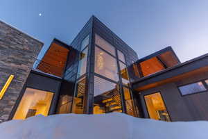 View of snowy exterior featuring a balcony and stone siding