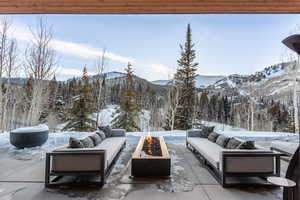 Snow covered patio featuring an outdoor living space with a fire pit, a patio, and a mountain view