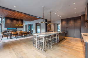 Kitchen with a large island with sink, modern cabinets, decorative light fixtures, a kitchen breakfast bar, and open floor plan