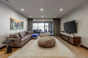 Living area with light wood-type flooring and recessed lighting