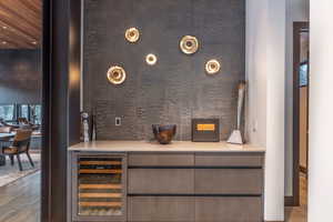 Indoor dry bar with wine cooler, modern cabinets, light stone counters, and recessed lighting