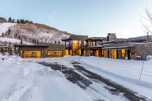 Snow covered property with stone siding, a balcony, a chimney, and a mountain view