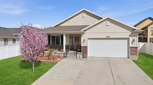 View of front of home with a garage, covered porch, brick siding, driveway, and roof with shingles
