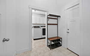 Laundry room featuring independent washer and dryer, light tile patterned flooring, and cabinet space