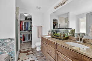 Full bath featuring double vanity, a spacious closet, and a shower stall