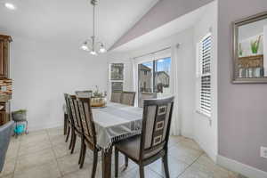 Dining room with vaulted ceiling, light tile patterned floors, and suspended lighting