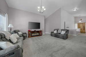 Living room with lofted ceiling, light carpet, and hanging lights