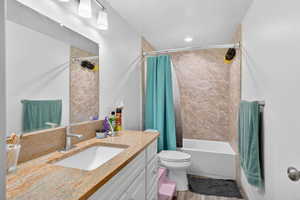 Bathroom featuring vanity, shower / tub combo, and light wood finished floors