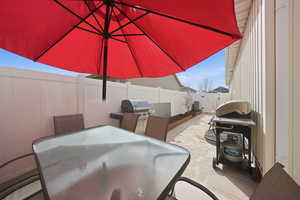 Fenced backyard with outdoor dining space, a grill, a patio area, and a gate