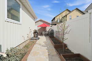 Fenced backyard with a vegetable garden, a patio, outdoor dining space, and a grill
