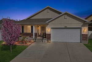 View of front of home with a porch, a garage, brick siding, and concrete driveway