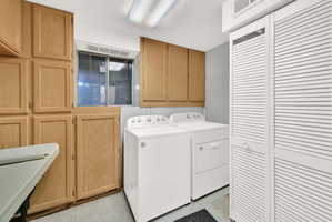 Laundry area featuring washer and dryer, cabinet space, and a textured ceiling