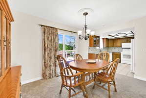 Dining room with light colored carpet and a chandelier
