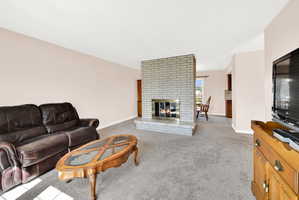 Living area with light colored carpet and a brick fireplace