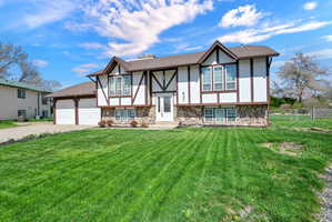 View of front facade with stucco siding, concrete driveway, a garage, stone siding, and a shingled roof