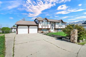 View of front facade with driveway, stone siding, an attached garage, a mountain view, and stucco siding