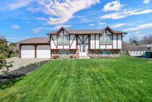 View of front of home with stucco siding, driveway, a front lawn, and an attached garage