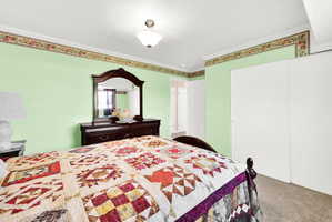 Bedroom with ornamental molding, carpet floors, and a closet