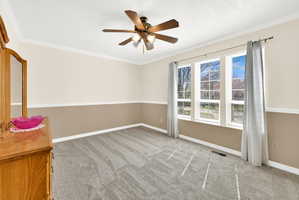 Spare room with crown molding, light colored carpet, and a ceiling fan