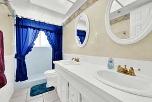 Bathroom featuring double vanity, a shower stall, and light tile patterned flooring