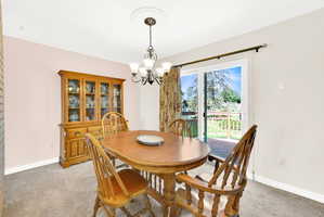 Dining area with hanging lights and light colored carpet