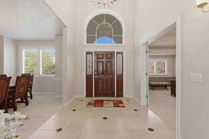 Foyer entrance featuring light carpet, suspended lighting, a high ceiling, and light tile patterned floors