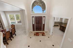 Entryway featuring a high ceiling, a chandelier, healthy amount of natural light, and light tile patterned floors