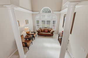 Living area with decorative columns, light carpet, and a high ceiling
