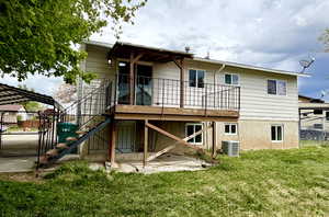 Rear view of property with mature trees, deck, and door to downstairs (under deck)