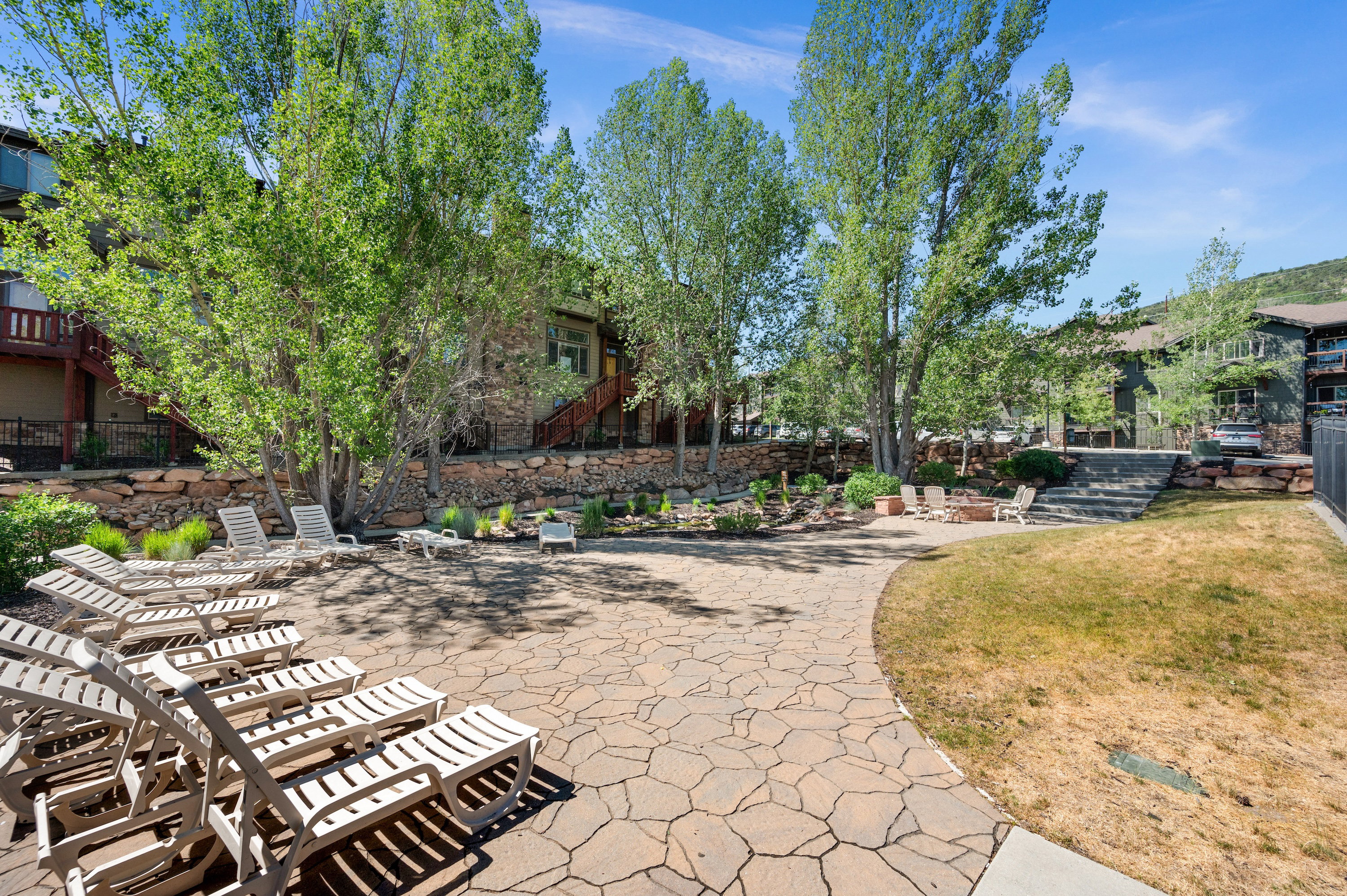 Expansive flagstone patio area featuring multiple lounge chairs and a central fire pit