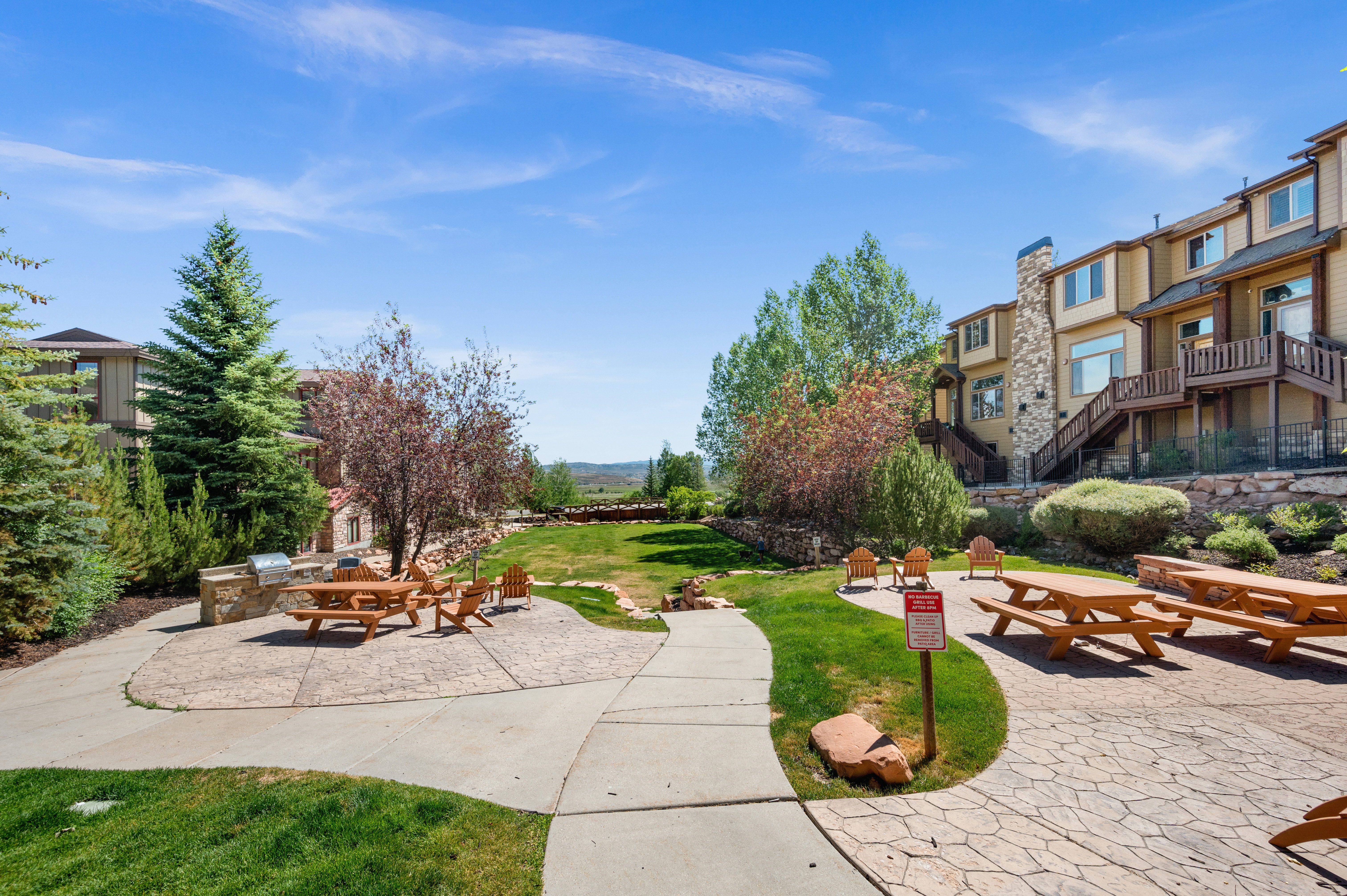 Expansive outdoor common area featuring stamped concrete patios, a built-in stone grill station, and multiple picnic table seating areas