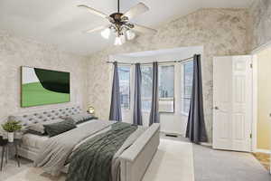 Bedroom with vaulted ceiling, light carpet, ceiling fan, and wallpapered walls