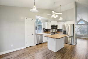 Kitchen featuring stainless steel appliances, vaulted ceiling, hanging light fixtures, a center island, and a ceiling fan
