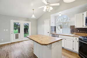 Kitchen featuring backsplash, white cabinetry, gas stove, ceiling fan, and light wood-style floors