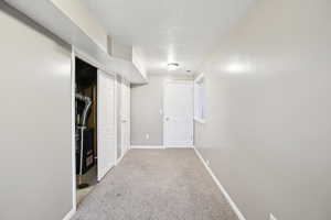 Hallway with a textured ceiling, light colored carpet, and heating unit