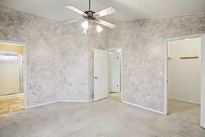Unfurnished bedroom with ensuite bath, light colored carpet, and a ceiling fan
