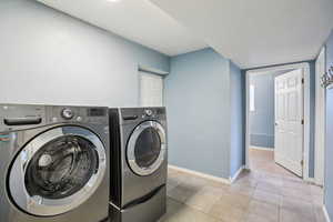 Laundry room with washer and dryer and light tile patterned floors