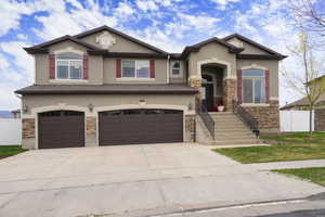 Craftsman inspired home featuring stone siding, stucco siding, and driveway