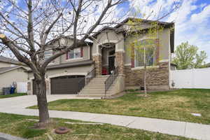 View of front of house with stucco siding, concrete driveway, stone siding, and an attached garage