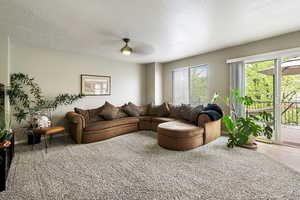 Carpeted living room featuring a textured ceiling and ceiling fan