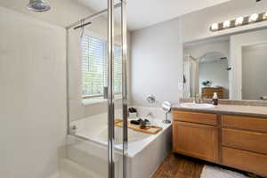 Bathroom featuring vanity, a bath, a shower stall, and dark wood-style flooring