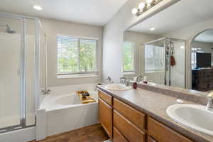 Full bath with double vanity, dark wood-style floors, a shower stall, a garden tub, and recessed lighting