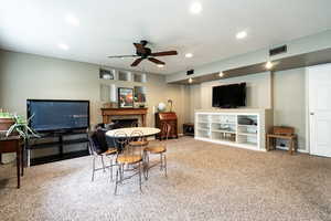 Carpeted dining room featuring a ceiling fan, a tiled fireplace, and recessed lighting
