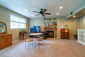 Dining space with a ceiling fan, a fireplace, light carpet, recessed lighting, and a textured ceiling