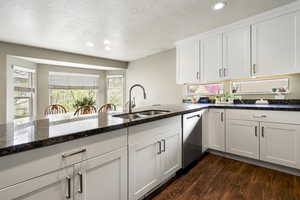Kitchen featuring white cabinetry, a textured ceiling, dark stone countertops, recessed lighting, and dishwasher